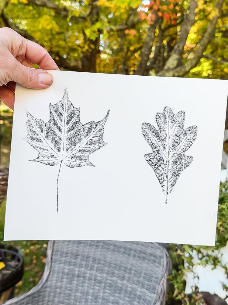 hand holding up a paper with leaf prints