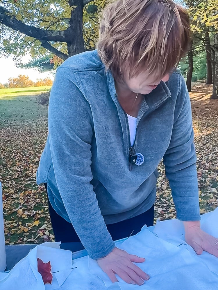 woman outside blotting a tray of wet leaves