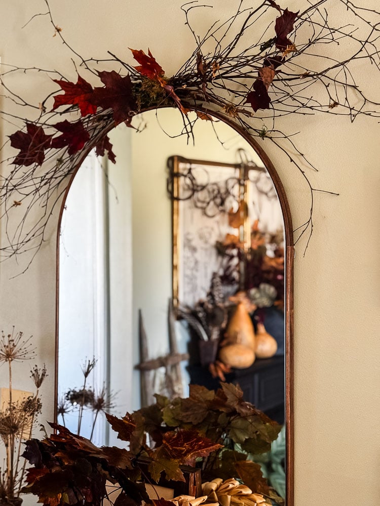 an arched mirror with branch swag above it