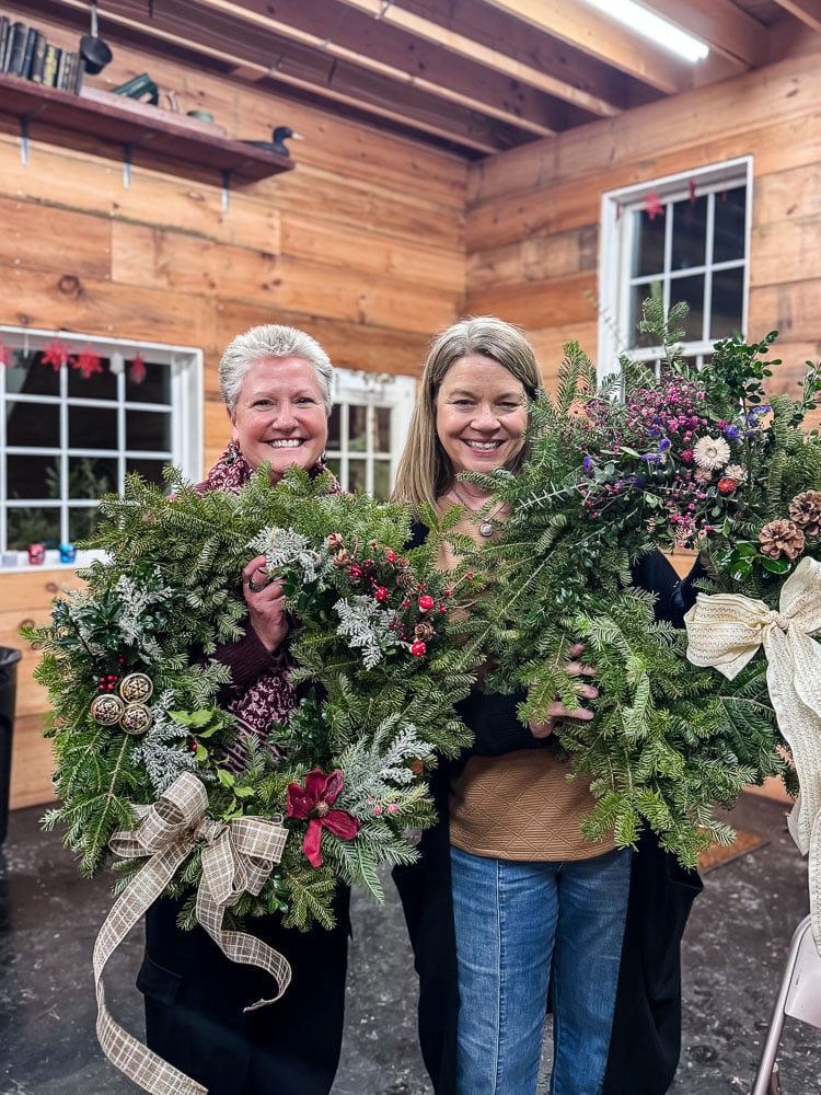 2 women holding up winter wreaths